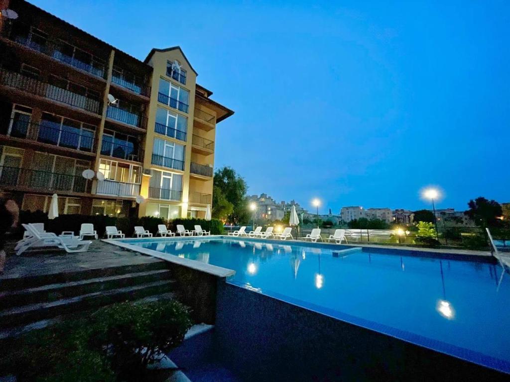 a swimming pool in front of a building at night at Sunny view South studio Мир Авангарда in Sunny Beach