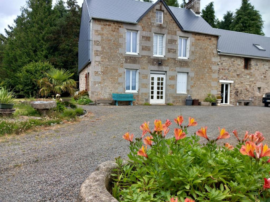une maison en pierre avec un banc bleu devant elle dans l'établissement Mont saint michel normandie, à Sainte-Cécile