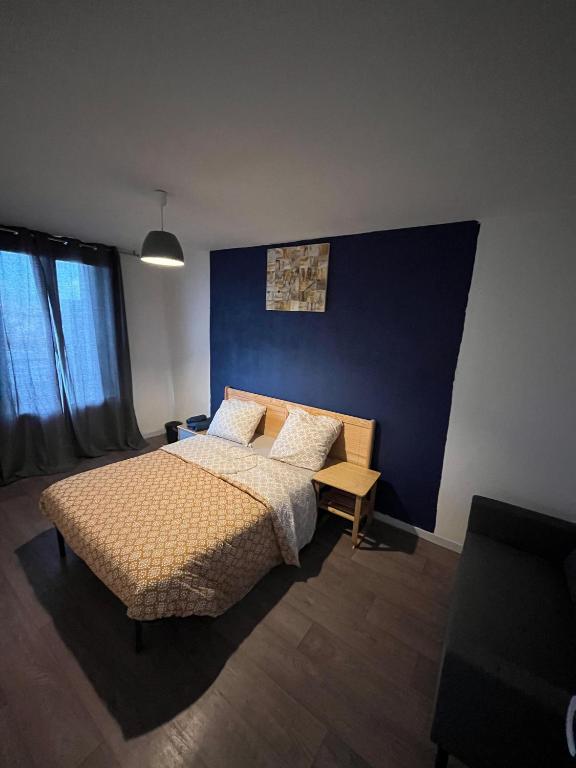une chambre avec un lit et un mur bleu dans l'établissement Chambre chez Bryan, à Toulouse
