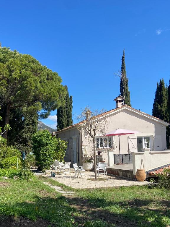 un bâtiment blanc avec des chaises et un arbre dans l'établissement Haut de villa avec jardin et vue dégagée, à Vence