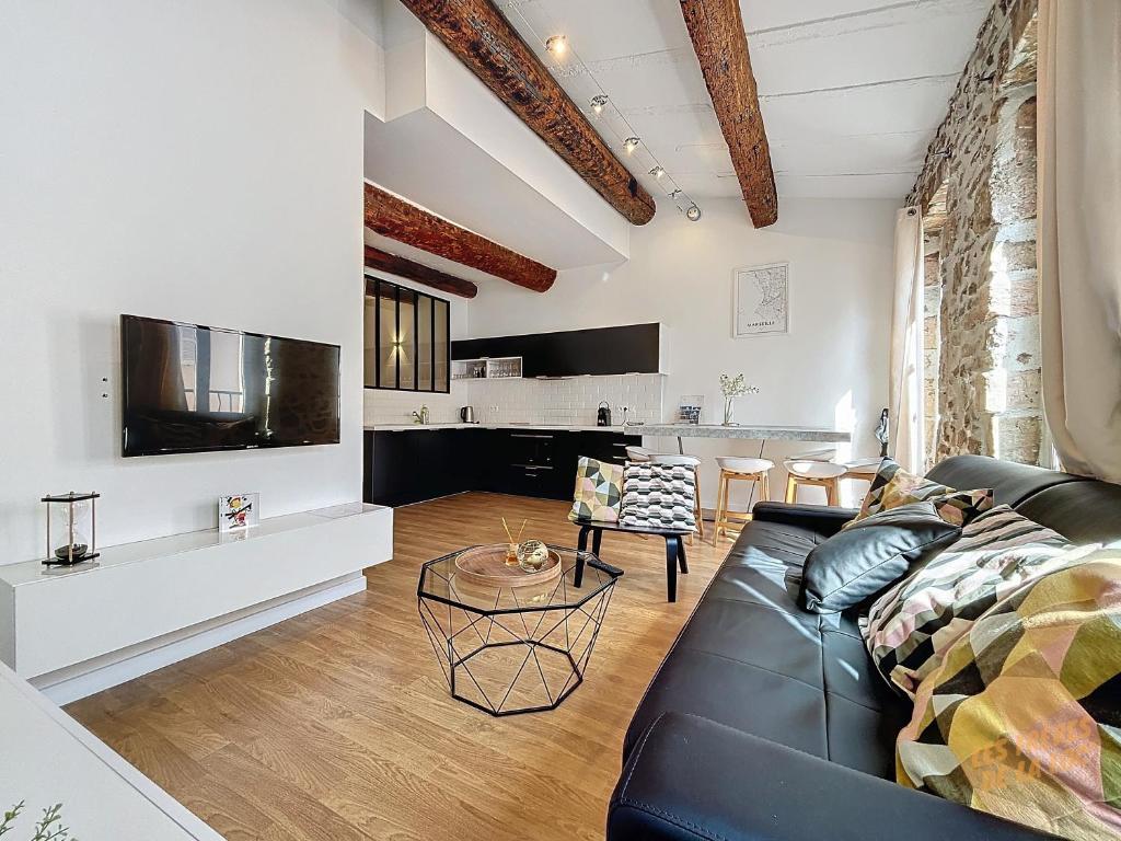 un salon avec un canapé noir et une télévision dans l'établissement Charmant Appartement au Vieux-Port - Climatisation - Les Frères de la Loc', à Marseille