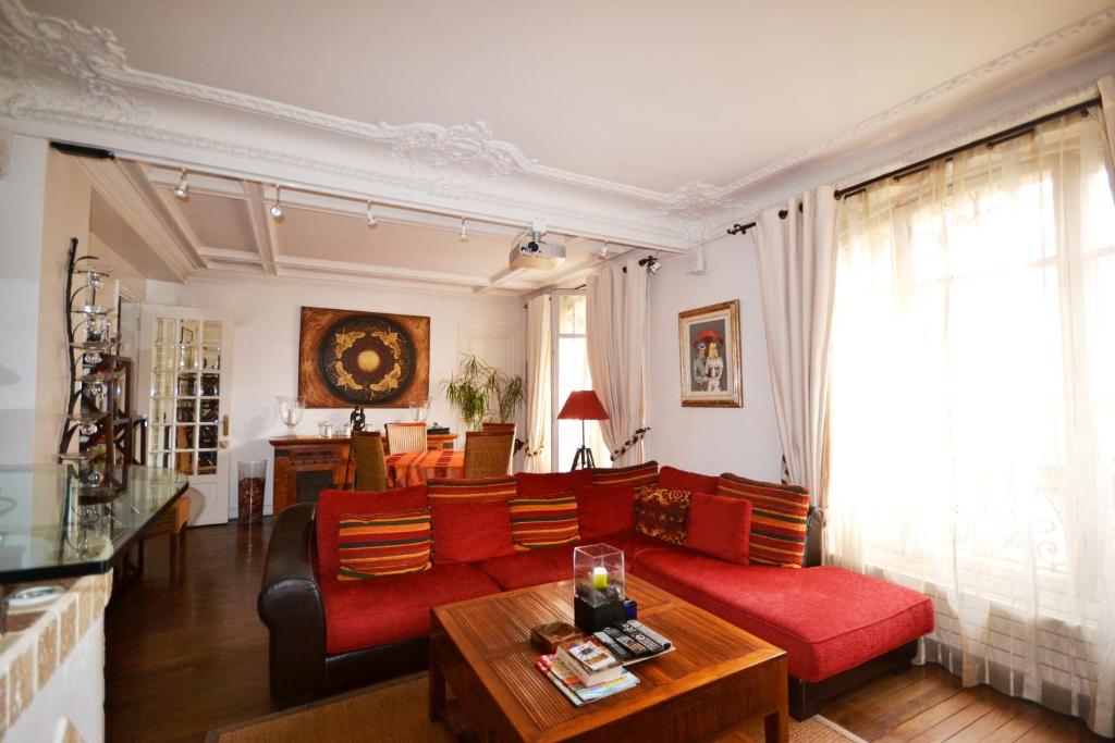 un salon avec un canapé rouge et une table dans l'établissement Great apartment near rue Daguerre, à Paris