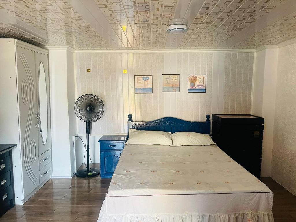 a bedroom with a bed with a blue headboard and a fan at Cozy House in Rose Hill