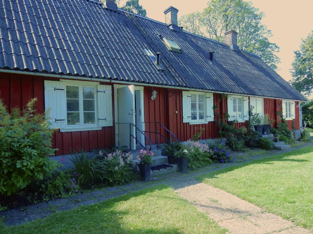 una casa roja con techo negro y flores en Swedish Idyll, en Årstad