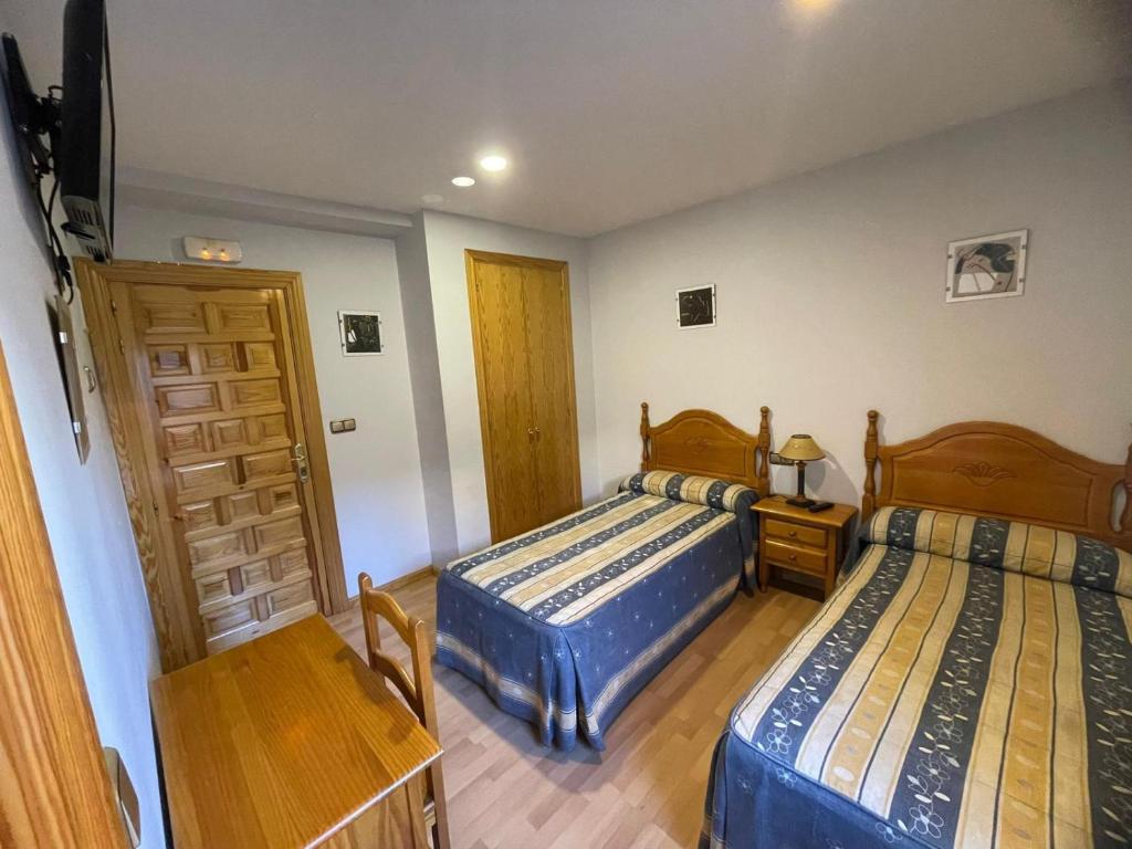 a bedroom with two beds and a wooden table at Pensión El Gallo in Olvega
