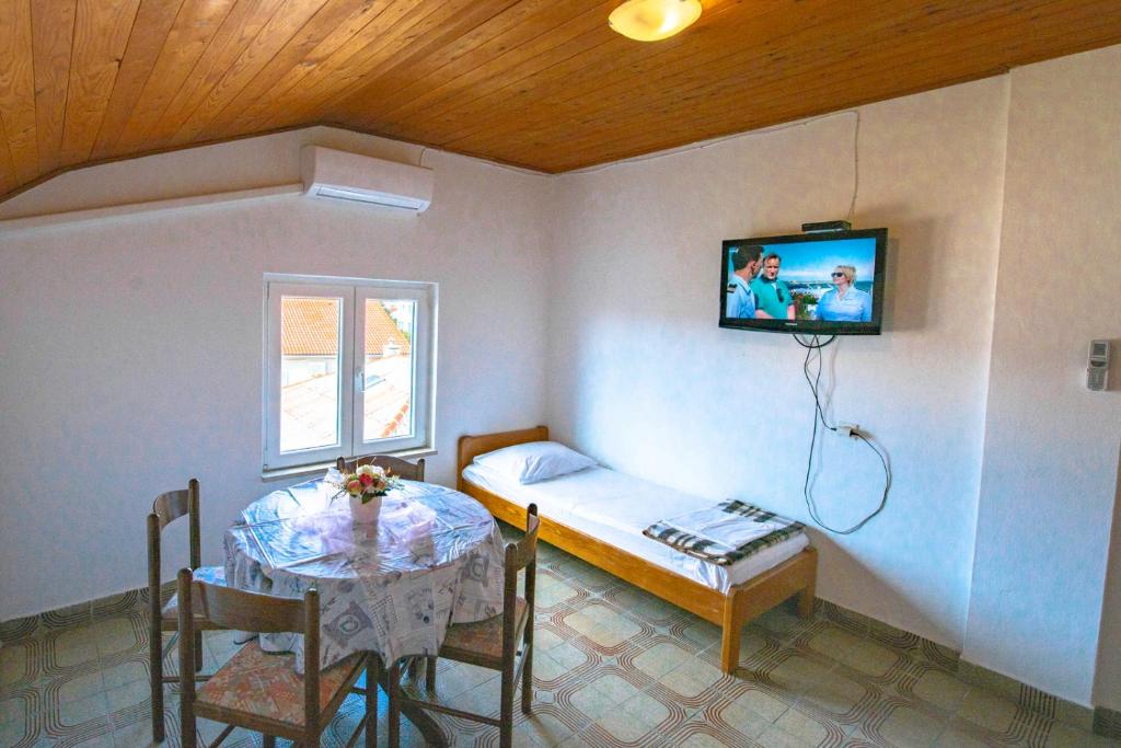 Pokój ze stołem, łóżkiem i telewizorem w obiekcie Apartments Matulo w Novalji