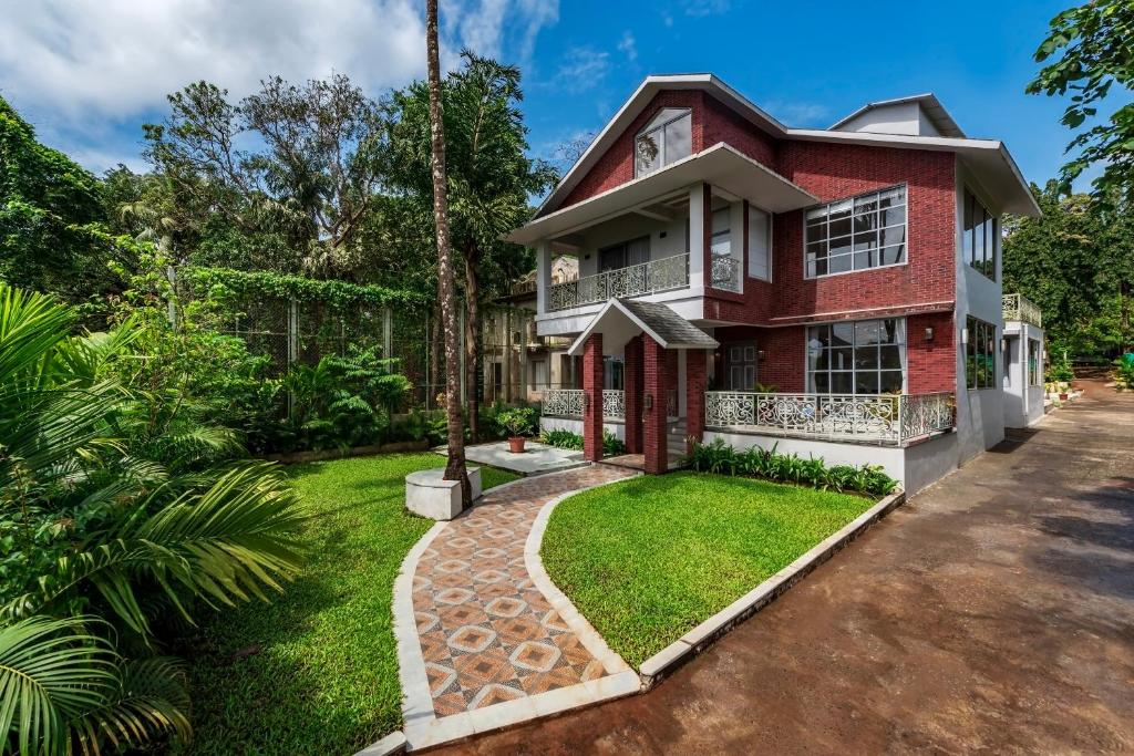 a red brick house with a green yard at SaffronStays Magnolias by River Moira in Bardez