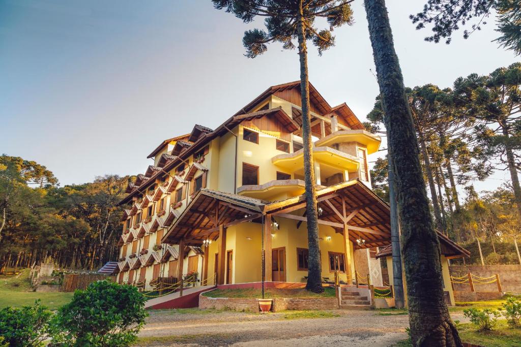 un grand bâtiment jaune avec des arbres devant lui dans l'établissement Hotel Guanxi, à Monte Verde