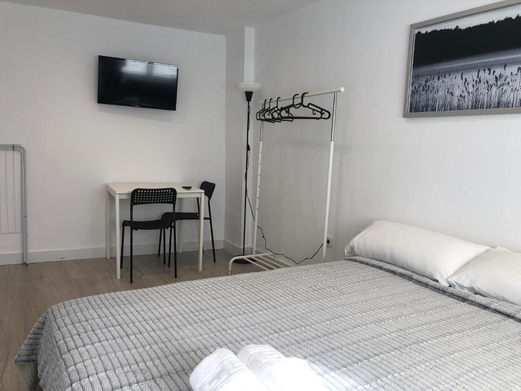 a bedroom with a bed and a table with a television at HABITACION ROOM Larga Temporada MAS DE 60 DIAS MALAGA CENTRO in Málaga