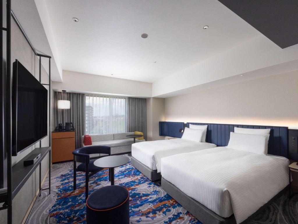 a hotel room with two beds and a flat screen tv at Novotel Nara in Nara