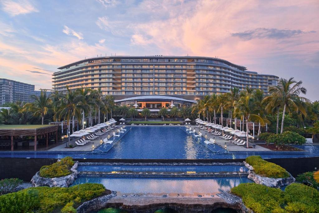 a large hotel with a swimming pool in front of a building at The Westin Blue Bay Resort & Spa in Lingshui