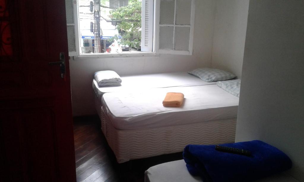 two beds in a small room with a window at Pousada Aloha in Santos