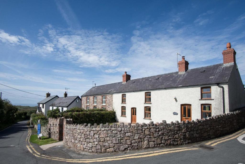 a large white house with a stone wall at The Cross - 4 Bedroom Cottage - Llangennith in Llangennith