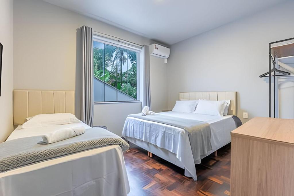 a bedroom with two beds and a window at Apartamentos a 600m da Vila Germânica in Blumenau