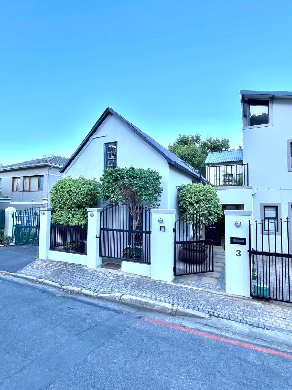 a white house with a black fence at Koetshuis on High Street in Paarl