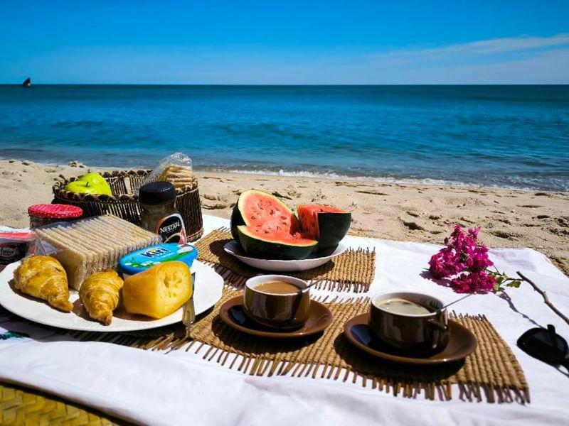 una mesa con comida en la playa con el océano en Bungalow Soa Majunga, en Mahajanga