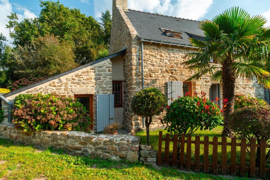 a stone cottage with a palm tree and a fence at La Libellule - Charmante maison avec jardin à Séné in Séné
