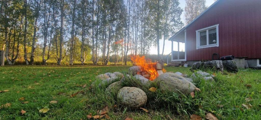 a fire in a field next to a red barn at gemütliches Ferienhaus - Höga Kusten Region in Ramsele
