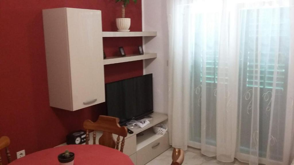 ein Wohnzimmer mit einem TV und einem Tisch mit einem Tisch in der Unterkunft Apartment ANTICA in Povlja