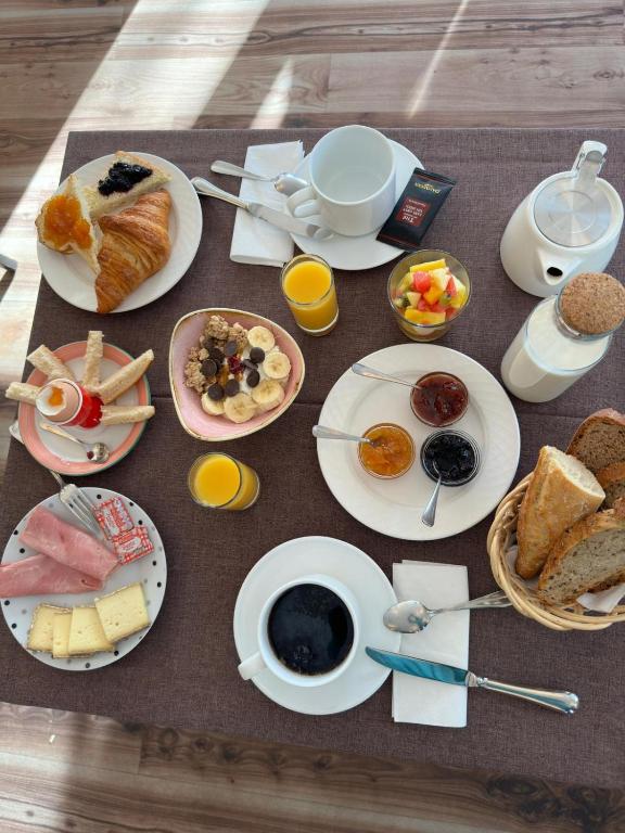 a table with plates of breakfast food on it at Hotel Le Faranchin in Villar-dʼArène