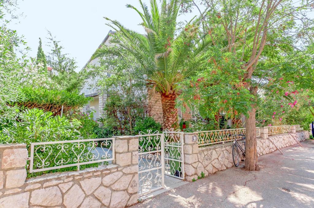 a stone fence with a palm tree in front of a house at Apartments Ivan in Novalja