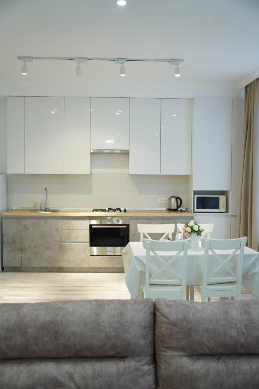 een keuken met witte kasten en een tafel en een bank bij Уютная однушка в центре города in Atıraw