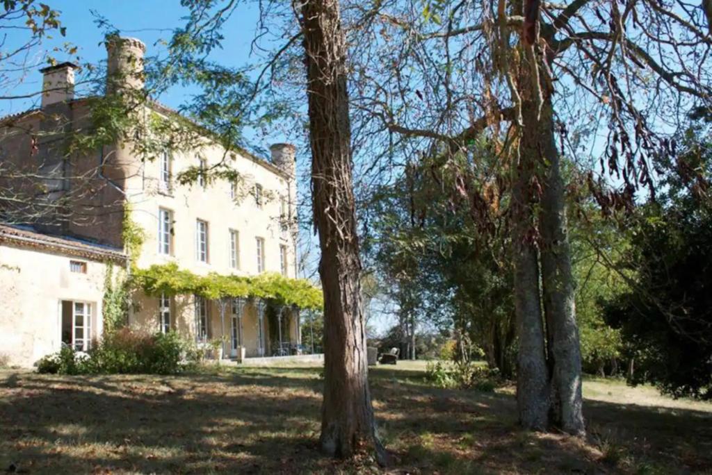 une grande maison blanche avec des arbres devant dans l'établissement Chambre d'hôtes Chateau de Fajac, à Pech-Luna