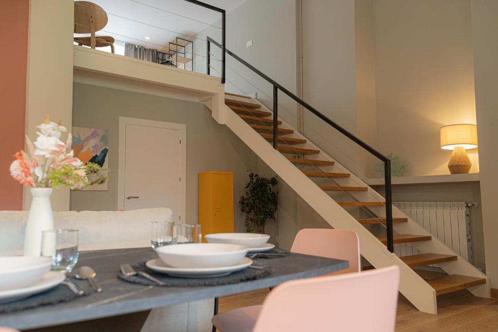 a dining room with a table and a staircase at Apartamento La Gaviota Gijón in Gijón