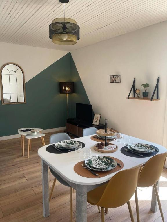 une salle à manger avec une table et des chaises blanches dans l'établissement Maisons Martigny B - Proche Futuroscope et Aquascope, à Chasseneuil-du-Poitou