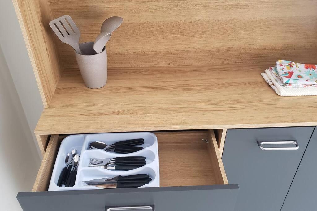 a drawer in a wooden cabinet with utensils in it at Casa Palmeira in Primavera do Leste