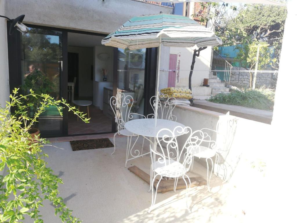 un patio avec une table, des chaises et un parasol dans l'établissement Appart Sympa au Calme, à Grasse
