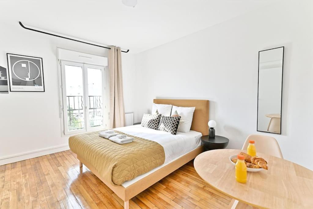 une chambre blanche avec un lit et une table dans l'établissement Studio spacieux et coloré - Montreuil II, à Montreuil
