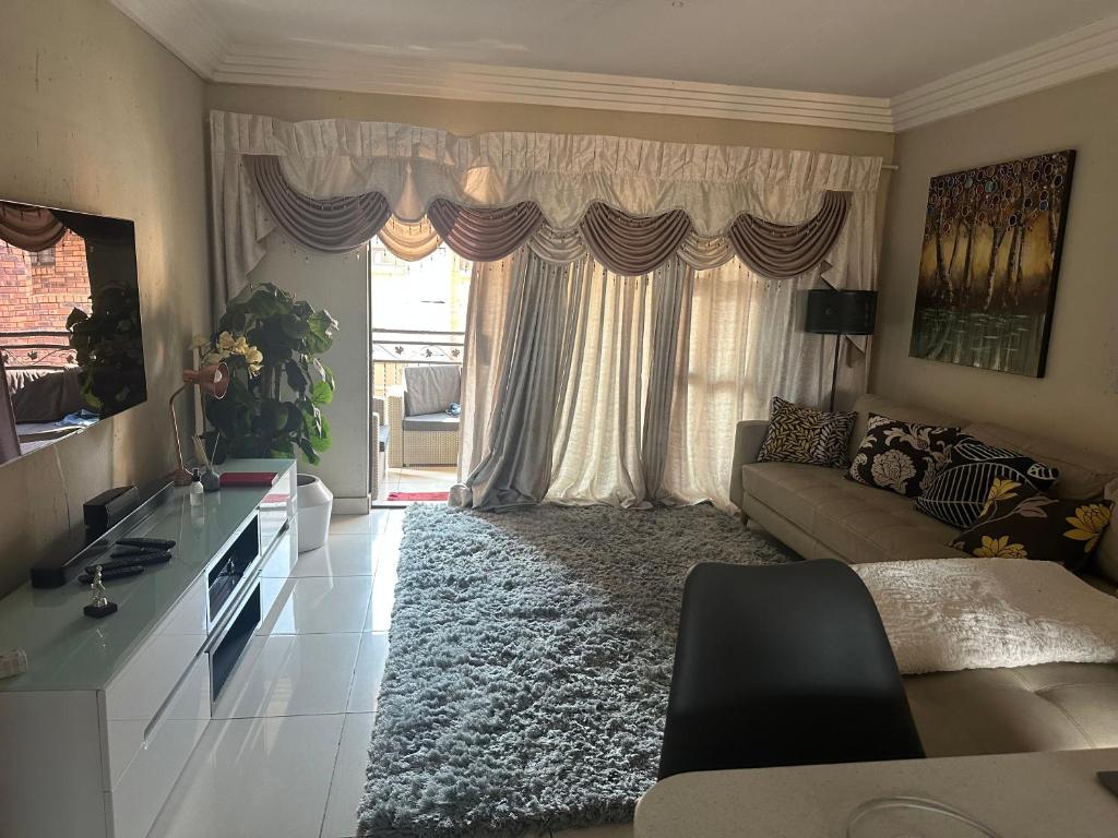 a living room with a couch and a large window at Ravenswood Mews in Boksburg
