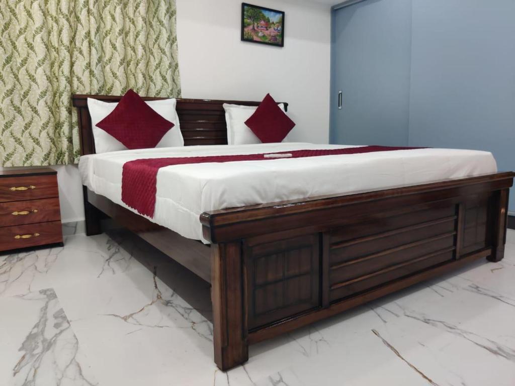 Un dormitorio con una cama de madera con almohadas rojas y blancas. en Srinidhi Home Stay, en Tirupati