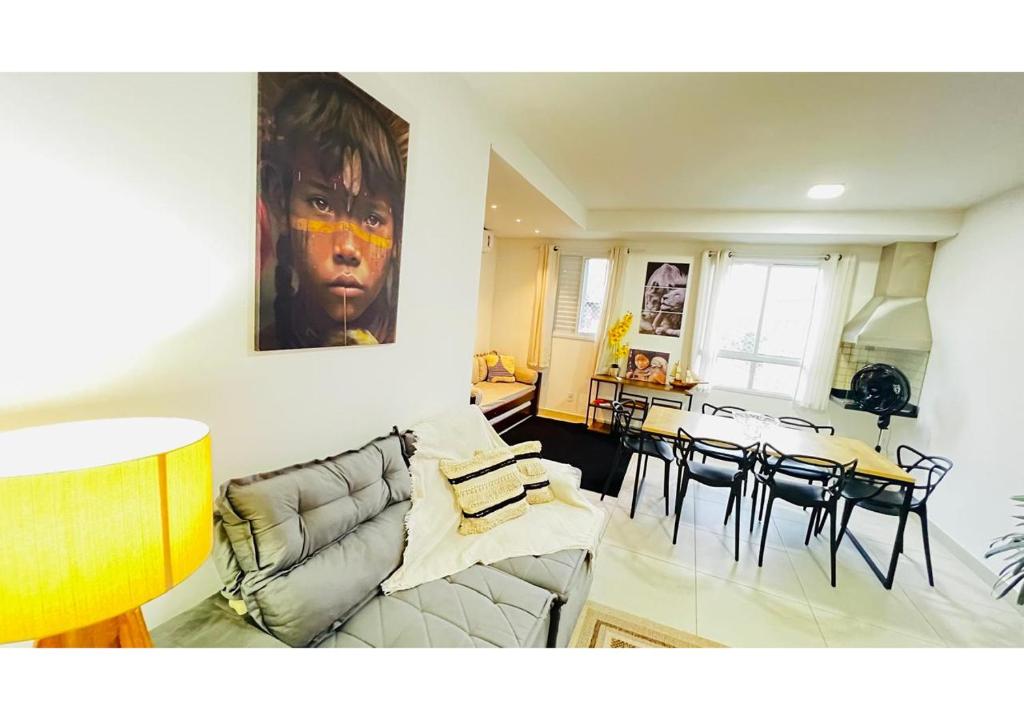 a living room with a couch and a table with chairs at Portal das Palmeiras 2 in Ubatuba