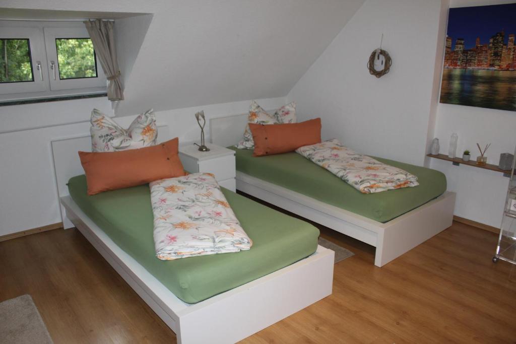 2 Betten in einem Zimmer mit grünen und orangefarbenen Kissen in der Unterkunft Appartementwohnung Antonia in Düsseldorf