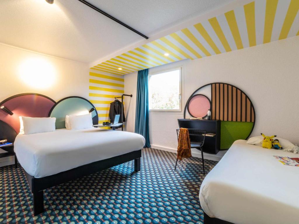 une chambre d'hôtel avec deux lits et une fenêtre dans l'établissement Ibis Styles Paris Saint Denis Pleyel, à Saint-Denis