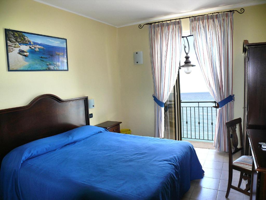 a bedroom with a blue bed and a balcony at B&B Miramare in Giardini Naxos