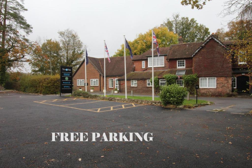 a building with flags in front of a parking lot at Trivelles Waterhall Country Gatwick Hotel & airport parking in Crawley