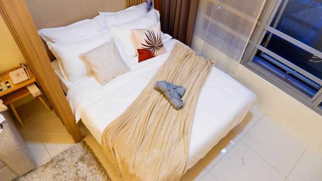 a bed with a blanket on it in a room at New Cozy Condo in Eastwood in Manila