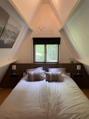 een slaapkamer met een wit bed met een raam bij Chalet 228 in Durbuy