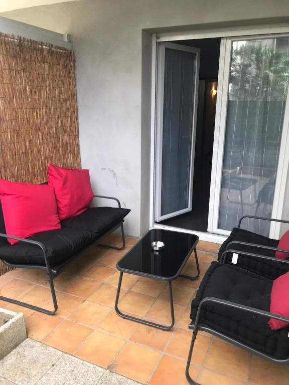 - un salon doté d'un mobilier noir et d'oreillers rouges dans l'établissement Cœur de ville, à Mont-de-Marsan