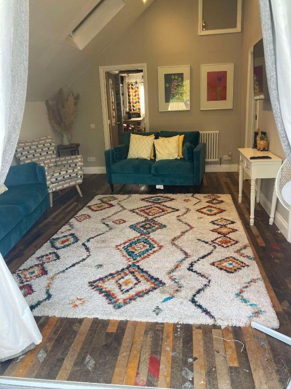 a living room with a blue couch and a rug at Lime Tree Cottage in Tillingham