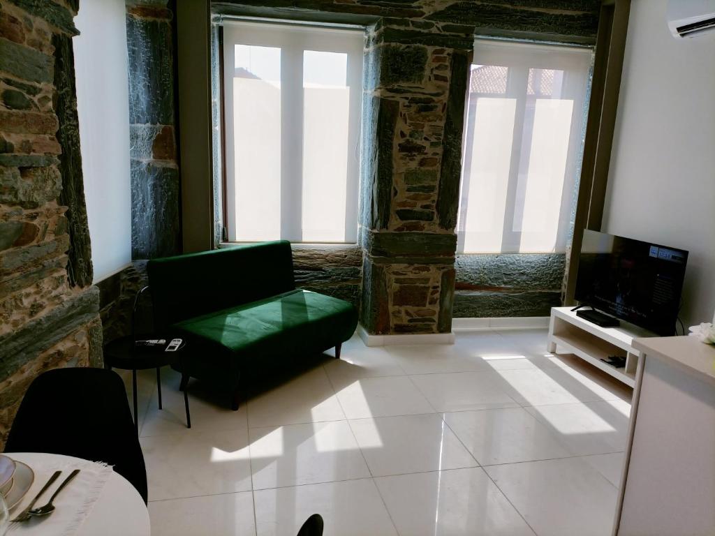Una sala de estar con un sofá verde y un televisor. en Valley Apartamentos T1, en Vila Nova de Foz Cõa