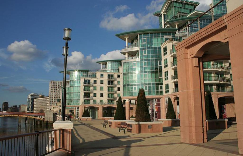 a large building in front of a street with benches at Aquarius at St. George Wharf in London
