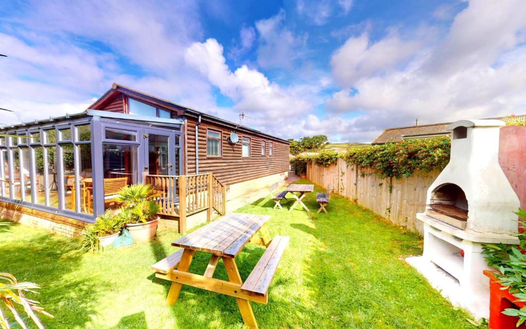 a small backyard with a wooden house and a grill at CROYDE DUNE LODGE 3 Bedrooms in Croyde