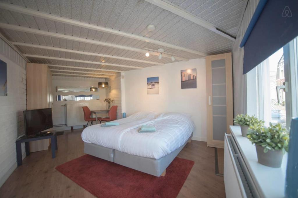 een slaapkamer met een bed, een bureau en een televisie bij Stop & Stay 2 in Zandvoort