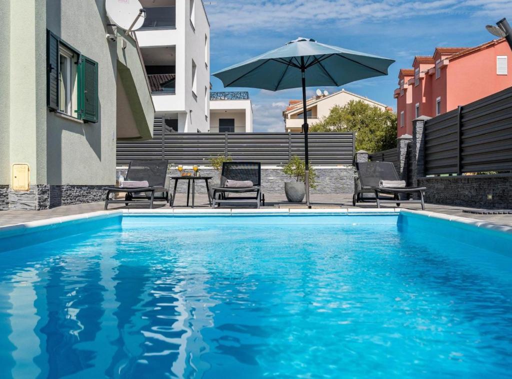 a swimming pool with an umbrella next to a building at Villa S in Vodice