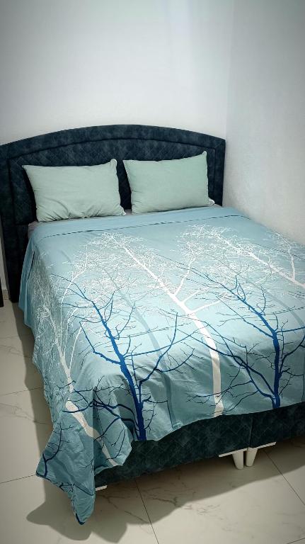 a bed with a blue comforter with branches on it at Park Apartment in Xanthi