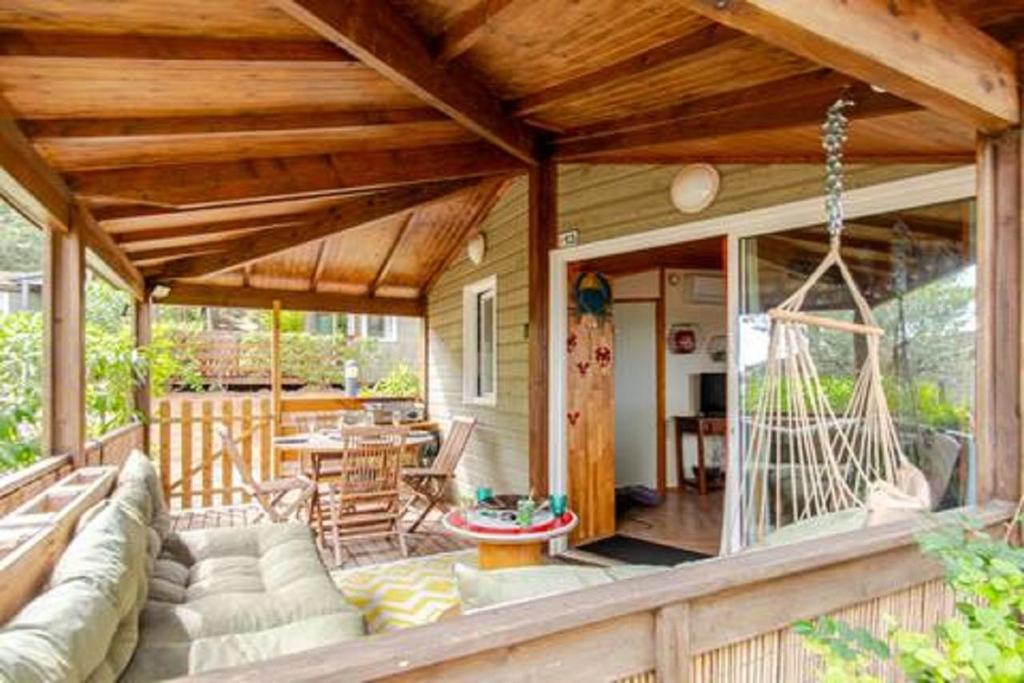 a porch of a house with a couch and a table at Chalet Mer et Pins in Agde